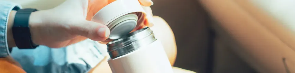 Close up of person's hands holding an insulated water bottle in a car